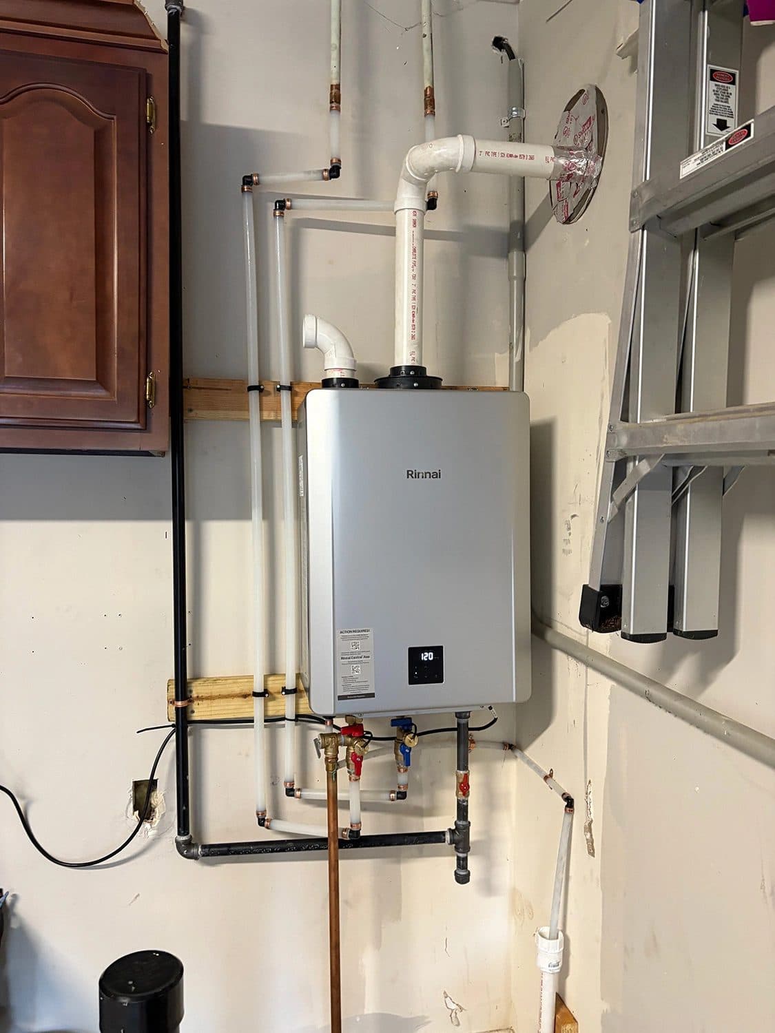 Rinnai tankless water heater installed on a garage wall with new gas and water connections
