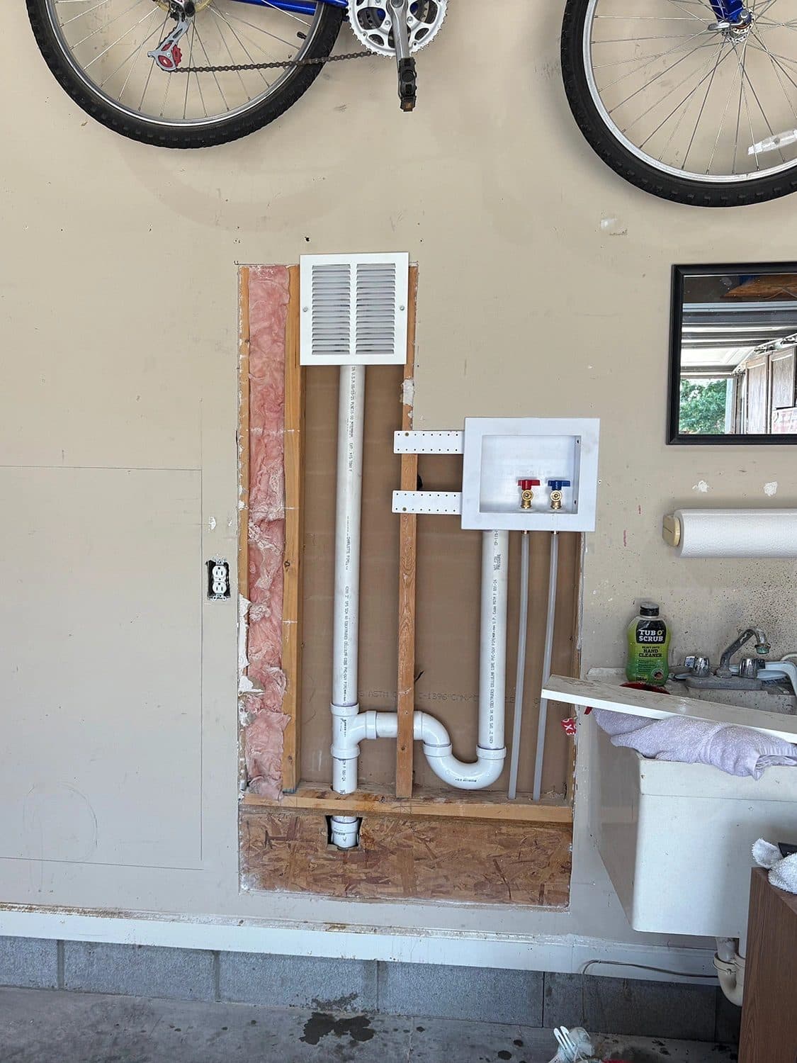 New drain line and washer box roughed into an open wall during a laundry room remodel